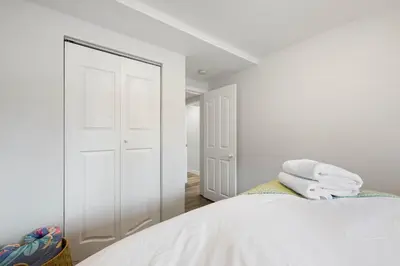 a white bedroom with a bed and a closet at 2BR Cozy Suite w Fireplace! FREE Banff Pass, Parking, Netflix! Near Golf Course! in Calgary