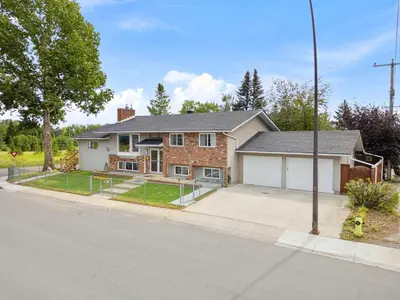 a brick house with a garage on a street at 2BR Cozy Suite w Fireplace! FREE Banff Pass, Parking, Netflix! Near Golf Course! in Calgary