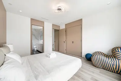 a bedroom with a large white bed and a chair at Charming and Modern Retreat in Vancouver Trendy 42nd Avenue Neighbourhood in Vancouver