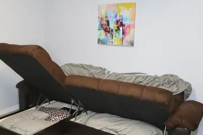 a brown couch sitting under a painting on a wall at Calgary's Home Cinema Retreat in Calgary