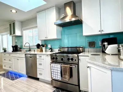 a kitchen with white cabinets and a stove top oven at Cozy 3BR Holiday Retreat 2 Free Parking AC King BD in Vancouver