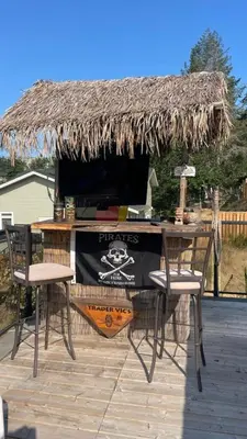 a table with two chairs and a thatch roof at Trader Vics Tiki Bar n Grill in Nanaimo