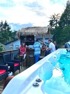 a group of people sitting at a bar next to a swimming pool at Trader Vics Tiki Bar n Grill in Nanaimo
