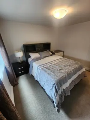 a bedroom with a bed and a lamp in it at Cozy Royal Bay Suite in Victoria