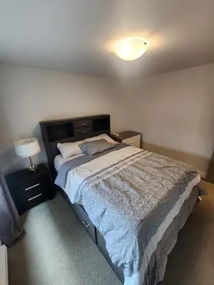 a bedroom with a bed and a light on the ceiling at Cozy Royal Bay Suite in Victoria