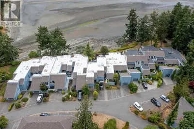 an aerial view of a building with cars in a parking lot at Aloha Cottage, Nanoose Bay - 2 Bdrm Oceanfront Unit with Private Deck in Nanoose Bay