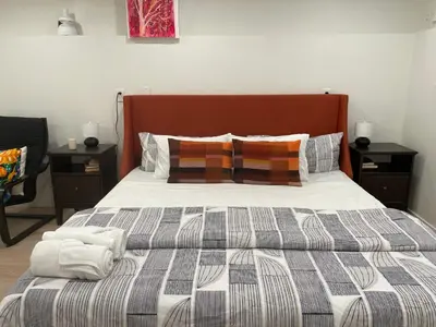 a bed with a striped comforter and pillows at Almost Home in West Vancouver