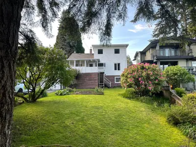 a large yard with a house and a tree at Almost Home in West Vancouver