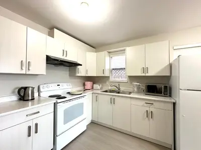 a kitchen with white cabinets and white appliances at Newly renovated 2 bed 1 bath in Ladner BC in Delta