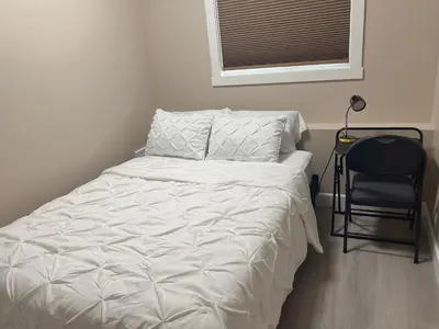 a bedroom with a bed and a chair and a window at Home away from home in Prince George