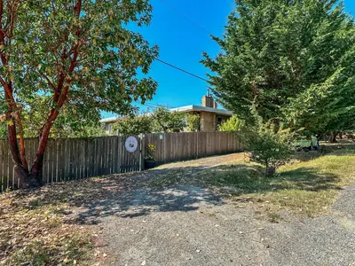 a fence in front of a house with a tree at Swallow's Perch Guest Suite in Vesuvius