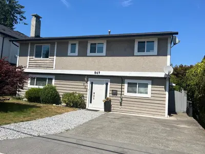 a large house with a driveway in front of it at Cozy Escape in the City in Port Coquitlam