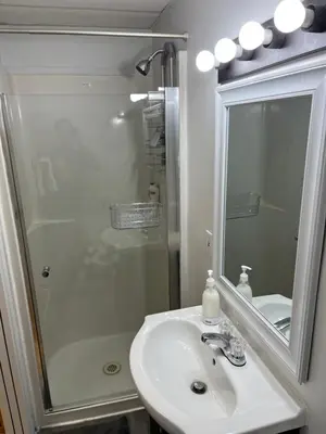 a bathroom with a shower and a sink and a mirror at Cozy Escape in the City in Port Coquitlam