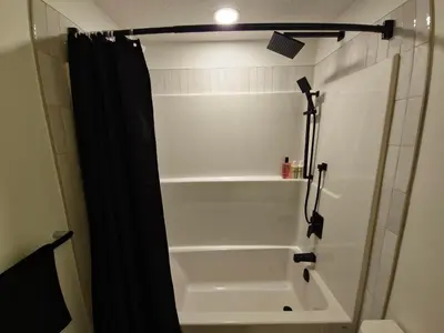 a shower with a black shower curtain in a bathroom at A stylish 2 BDR with a blend of cozy and peace! in Calgary