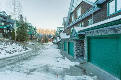 a snowy street with green garage doors on a house at Cedar Ridge Estates by StayIn in Fernie