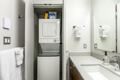 a bathroom with a washer and dryer next to a sink at Executive Condo In Old Town Victoria in Victoria
