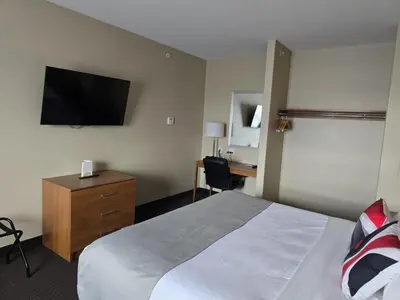 a hotel room with a bed and a television on the wall at The Kanata Bonnyville in Bonnyville