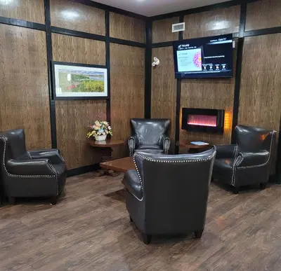 a waiting room with leather chairs and a tv at The Kanata Bonnyville in Bonnyville