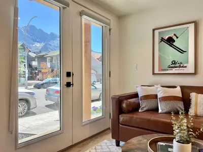 a living room with a couch and a glass door at Special! New Downtown Mtn View Free Parking 2b&2b in Canmore