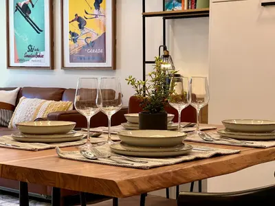 a wooden table with wine glasses and plates on it at Special! New Downtown Mtn View Free Parking 2b&2b in Canmore