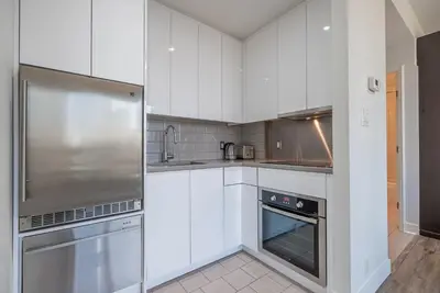 a kitchen with white cabinets and a stainless steel refrigerator at Gorgeous City Views Central Studio Walk to Seawall in Vancouver
