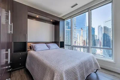 a bedroom with a bed and a large window at Gorgeous City Views Central Studio Walk to Seawall in Vancouver