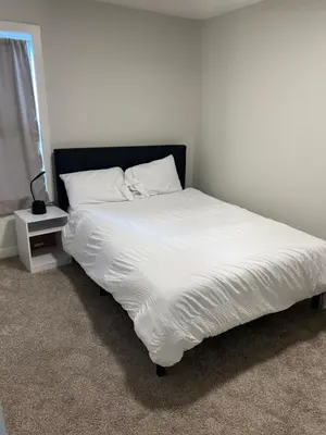 a white bed with a black headboard and white sheets at Beautiful suite in Balzac