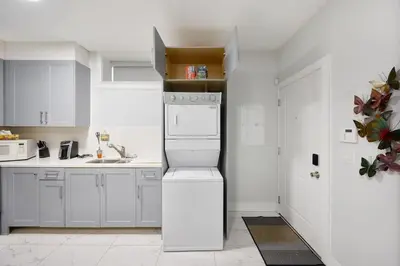 a white kitchen with a sink and a dishwasher at Basement Suite In Vancouver in Vancouver