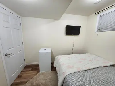 a bedroom with a bed and a tv on the wall at Basement Apartment in Calgary