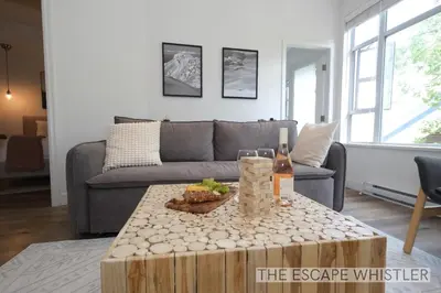 a living room with a couch and a table with a bottle of wine at Whistler Village 2BR 2BA Top-Floor Condo with Hot Tub and Parking in Whistler
