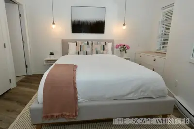 a bedroom with a large white bed and a couch at Whistler Village 2BR 2BA Top-Floor Condo with Hot Tub and Parking in Whistler