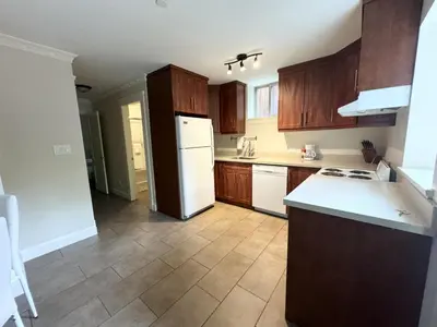a kitchen with wooden cabinets and a white refrigerator at Cozy 1BR Near Skytrain - Explore Vancouver Easily in Vancouver