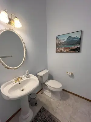 a bathroom with a sink and a toilet and a mirror at Luxury bungalow in NW Calgary in Calgary