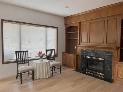 a living room with a fireplace and two chairs and a table at Luxury bungalow in NW Calgary in Calgary
