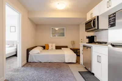 a small bedroom with a bed and a kitchen at Exquisite One Bedroom Apartment in NW in Calgary