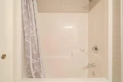 a bathroom with a tub and a shower curtain at Exquisite One Bedroom Apartment in NW in Calgary
