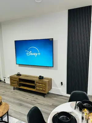 a living room with a flat screen tv on a wall at The Glacier Royale - 1 Bed Suite in NW Calgary in Calgary