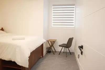 a bedroom with a bed and a chair next to a window at New Luxury Walkout Suite Near University-BY ROOM in Calgary