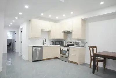 a kitchen with white cabinets and a wooden table at New Luxury Walkout Suite Near University-BY ROOM in Calgary