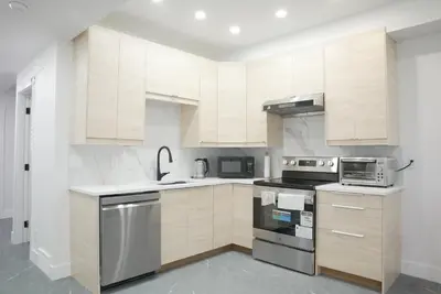 a kitchen with white cabinets and stainless steel appliances at New Luxury Walkout Suite Near University-BY ROOM in Calgary