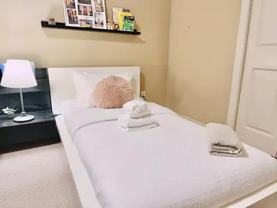 a bedroom with a white bed with towels on it at Scorpio House Langley - Semi-basement Suite in Langley