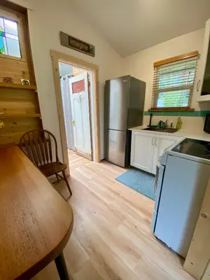 a kitchen with a refrigerator and a table and a table at Little Cabin in Middlepoint in Halfmoon Bay