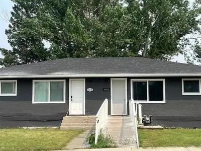 a gray house with a porch and a tree at Cute HighlandPark House in Calgary