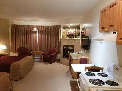 a kitchen and living room with a couch and a stove at New Imperial Suites in Whitecourt