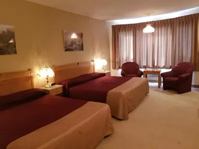 a hotel room with two beds and a table and chairs at New Imperial Suites in Whitecourt