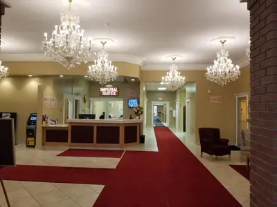 a lobby with chandeliers and a red carpet at New Imperial Suites in Whitecourt