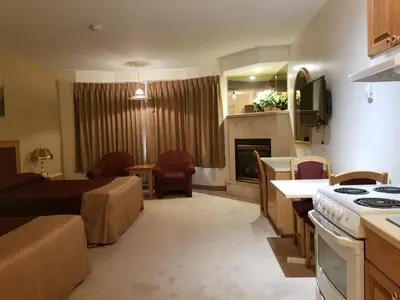 a kitchen and living room with a couch and a stove at New Imperial Suites in Whitecourt