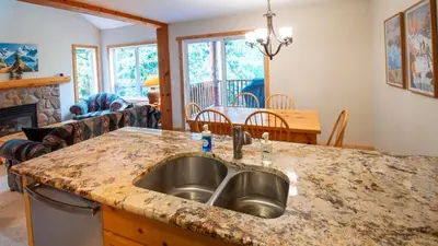 a kitchen with a sink and a living room at Stone Creek Chalet by Fernie Lodging Company in Fernie