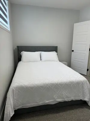 a bedroom with a large bed with white sheets at Chic & Cozy 2-BR Suite at Glacier Ridge NW Calgary in Calgary