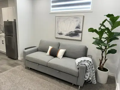 a gray couch in a kitchen with a plant at Chic & Cozy 2-BR Suite at Glacier Ridge NW Calgary in Calgary